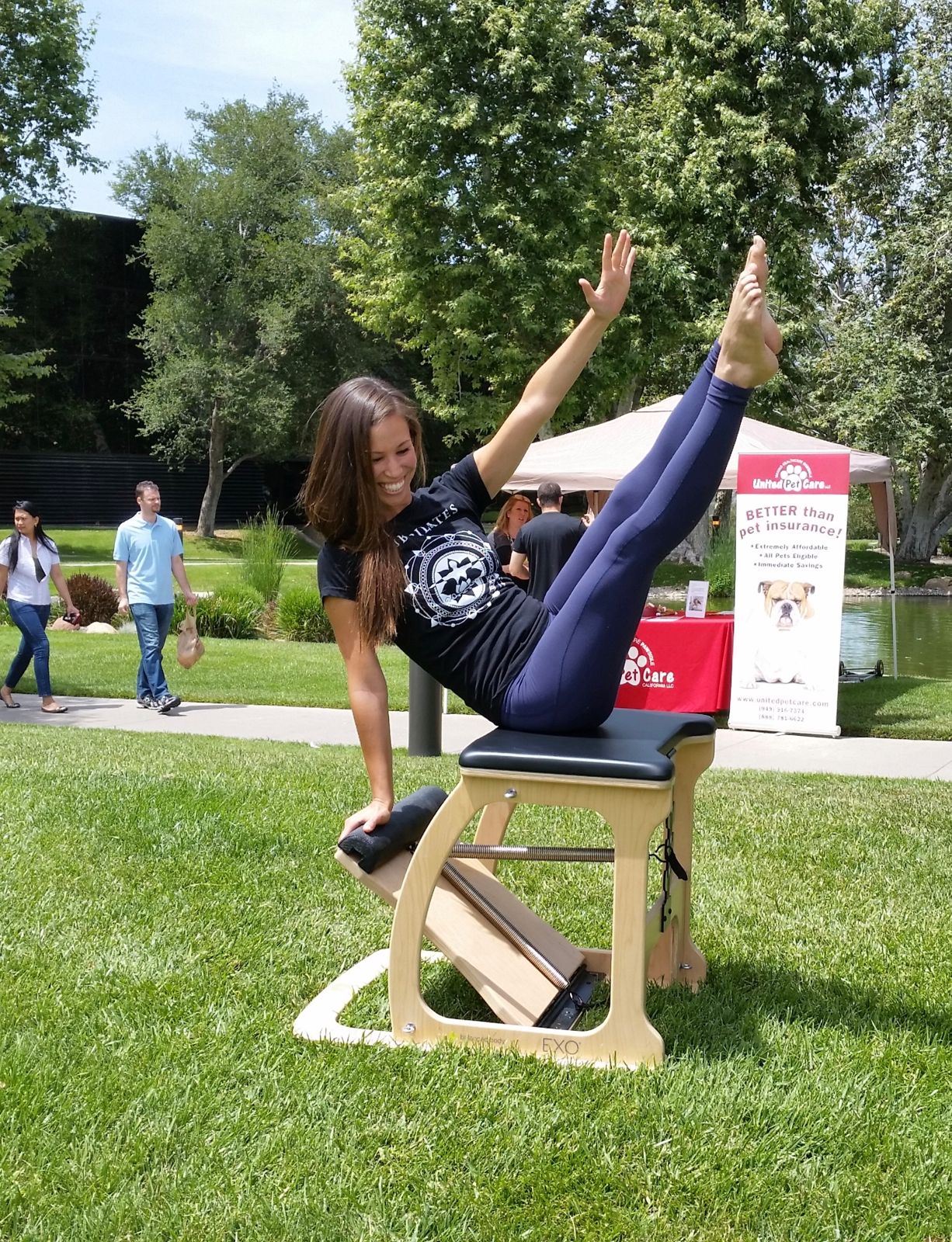 Instructor demonstrating a Pilates chair on a lawn at a corporate event